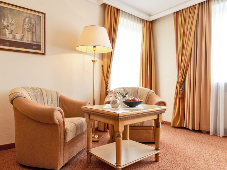Die Sitzecke mit zwei bequemen Sesseln und Tisch im Zimmer Typ 11 des Wellnesshotels Mooshof in Bodenmais laden zum Entspannen ein.
