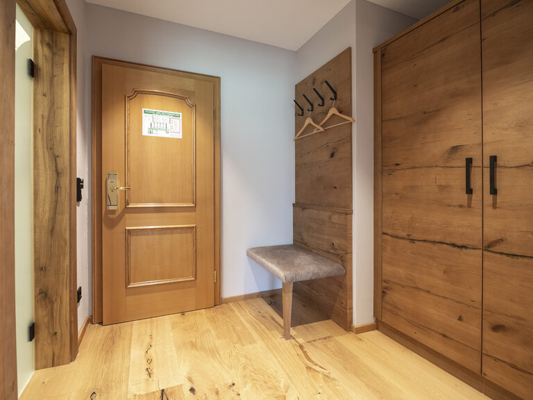 Der Eingang des Zimmer Typ 4 im Wellnesshotel Mooshof im Bayerischen Wald mit Holztüren und großem Kleiderschrank.