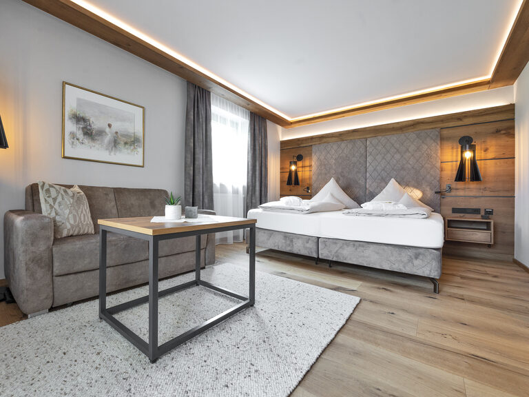 Komfortables Zimmer Typ 4 mit Bett und bequemer Couch für einen Aufenthalt im Wellnesshotel Mooshof im Bayerischen Wald.