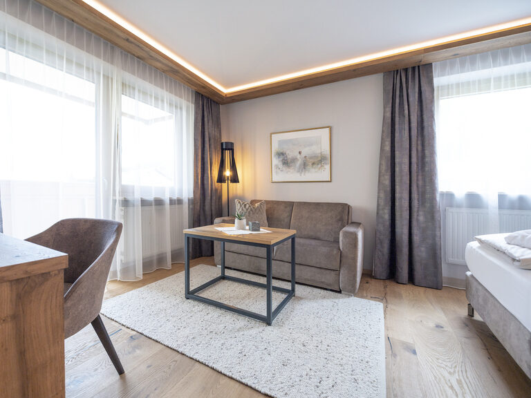 Die gemütliche Sitzecke mit viel Tageslicht und modernen Designelementen im Zimmer Typ 4 des Wellnesshotels Mooshof im Bayerischen Wald.