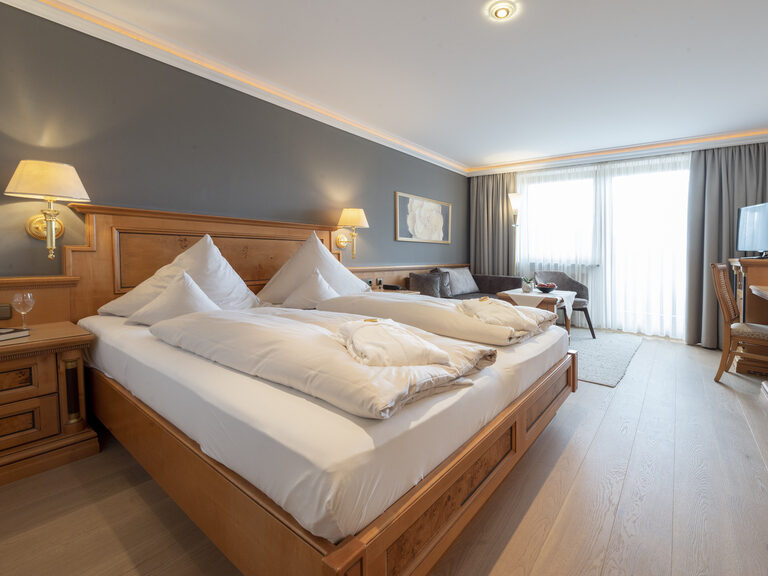 Das große Bett aus Holz steht im komfortablen Zimmer Typ 9 des Wellnesshotels Mooshof in Bayern.
