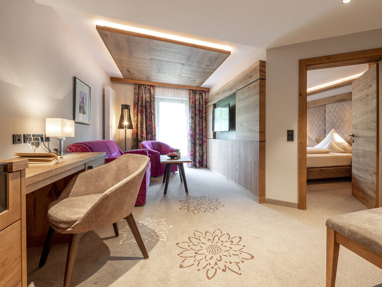 Ein Blick in das Zimmer Typ 1 des Wellnesshotels Mooshof in Bodenmais mit praktischer Arbeitsfläche und komfortablem Bett und Sitzmöglichkeiten.