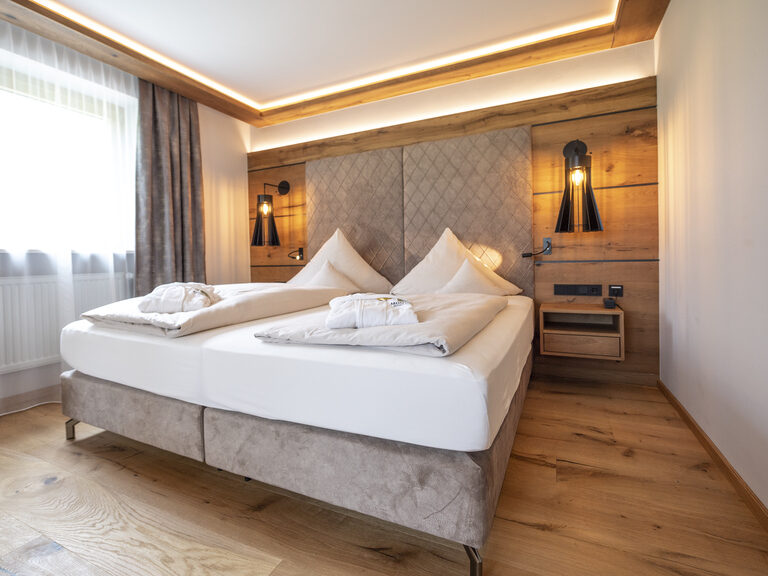 Das Licht durchflutete Suite-Zimmer Typ 4 im Wellnesshotel Mooshof in Bodenmais mit einem komfortablen Doppelbett.