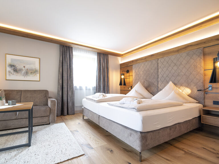 Das Hotelzimmer Typ 4 im Wellnesshotel Mooshof in Bodenmais mit großzügigem Bett und einladenden Sesseln für entspanntes Verweilen.