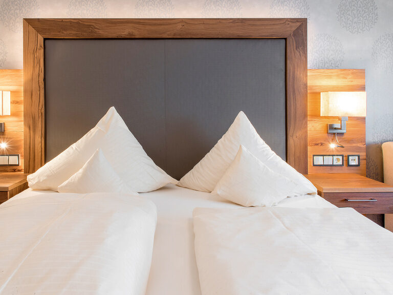 Bett mit schneeweißer weichen Bettwäsche und Kopfkissen in Zimmer Typ 5 des Wellnesshotels Mooshof im Bayerischen Wald.