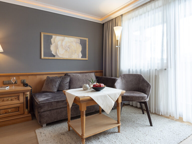 Im Zimmer Typ 9 des Wellnesshotels Mooshof im Bayerischen Wald schaffen ein Sofa und Sessel mit Couchtisch einladende Sitzgelegenheiten zum Entspannen.